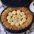 A round navy tin of Zalatimo Sweets featuring a selection of delicately crafted Middle Eastern cookies, including crispy sesame and almond biscuits, arranged attractively, with a cup of coffee beside it, emphasizing the luxurious dessert experience.