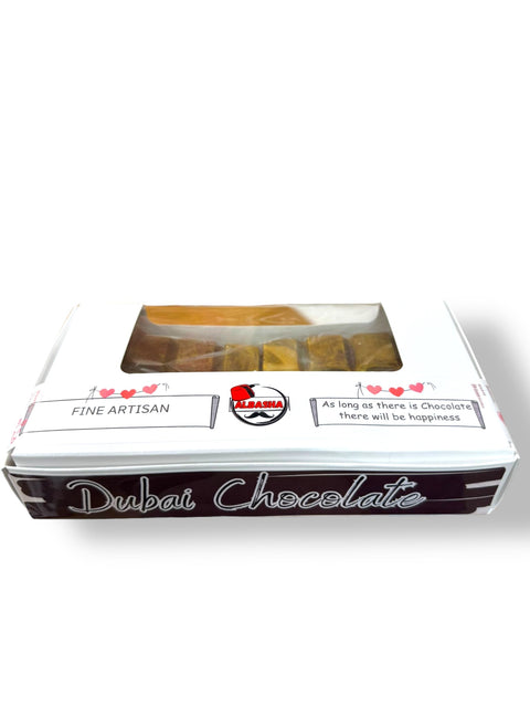 A beautifully crafted box of Dubai Chocolate from ALBASHA, displaying kunafeh pistachio pieces through a clear window, with the label indicating it as a fine artisan chocolate.